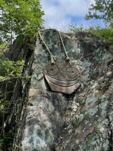 Smiley face hanging from side of a rock.