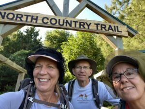 Three hikers under a North Country Trail sign.